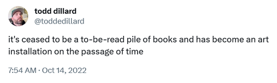 tweet from @toddedillard stating 'it's ceased to be a to-be-read pile of books and has become an art installation on the passage of time'